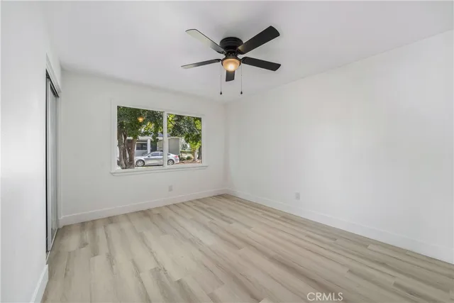 an empty room with ceiling fan and window