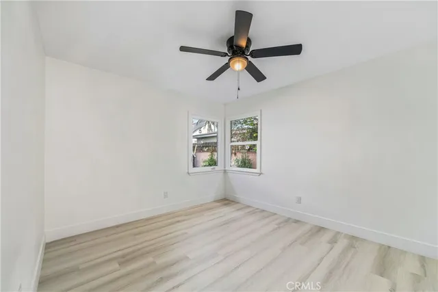 an empty room with wooden floor and ceiling fan