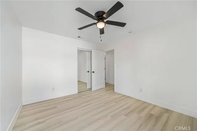 an empty room with a window and a ceiling fan