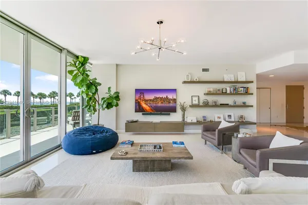 a living room with furniture a chandelier and a flat screen tv