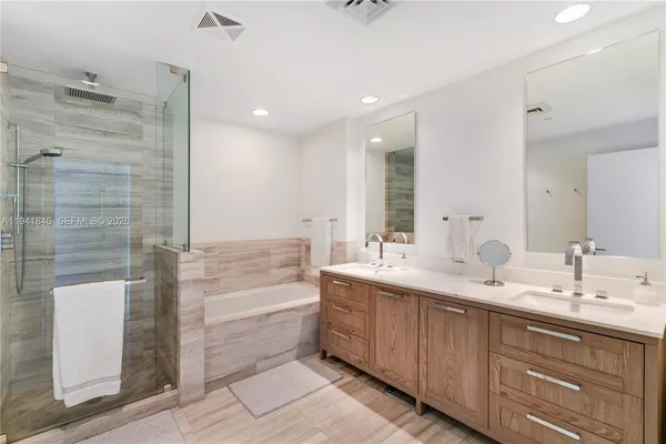 a bathroom with a double vanity sink a mirror and a bathtub