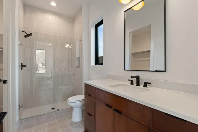 a bathroom with a double vanity sink toilet mirror and shower