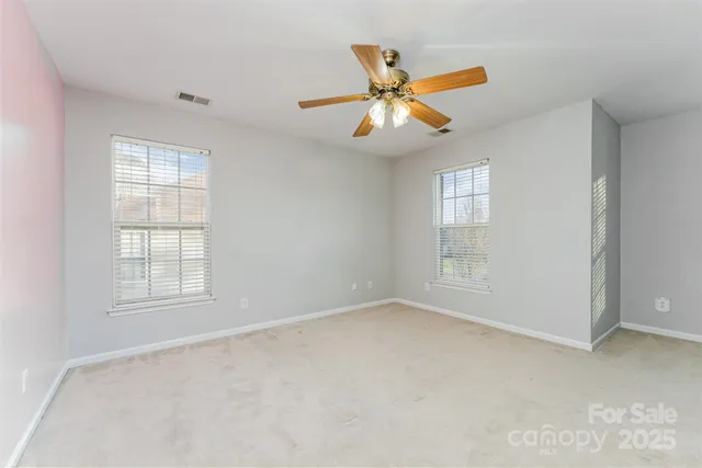 an empty room with windows and fan