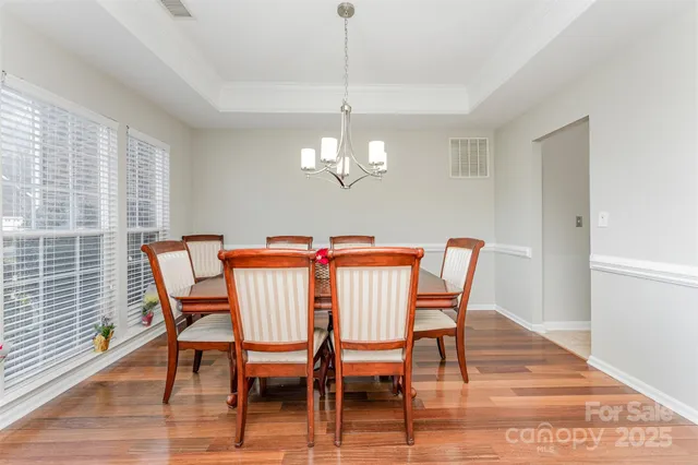 a dining room with furniture wooden floor a rug and a chandelier