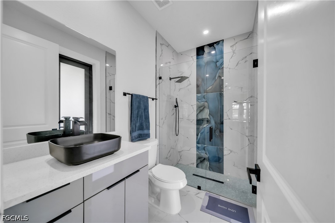 1128 Nelson Road North Cape Coral, FL 33993 - Photo 10 of 22 a bathroom with a sink a toilet a mirror and shower