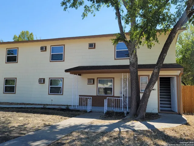 a view of a house with wooden fence and a large tree