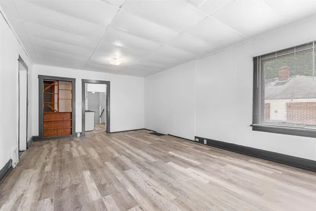 a view of an empty room with wooden floor and a window