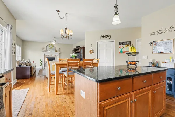 a room with stainless steel appliances kitchen island granite countertop a dining table chairs and a refrigerator