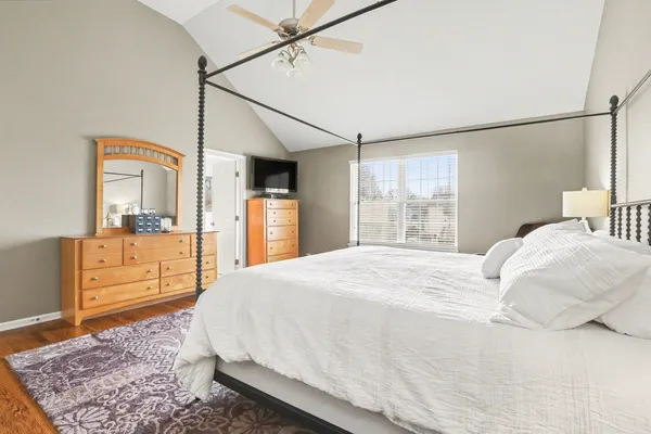 a bedroom with a large bed and dresser with mirror