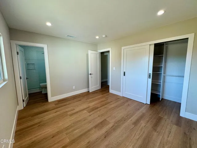 an empty room with wooden floor & closet area