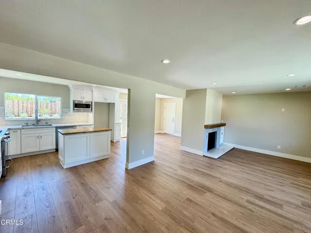 a large kitchen with a center island wooden floor and stainless steel appliances