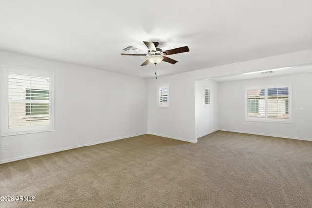 a view of an empty room with a ceiling fan and window