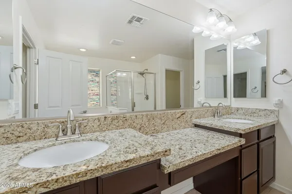 a bathroom with a granite countertop double vanity sink and a mirror
