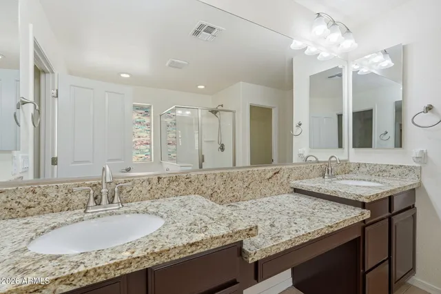 a bathroom with a granite countertop double vanity sink and a mirror