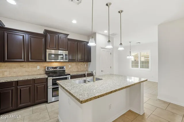 a kitchen with stainless steel appliances granite countertop a sink a stove and a wooden floors