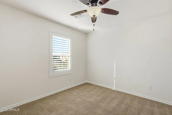 an empty room with a window and a fan