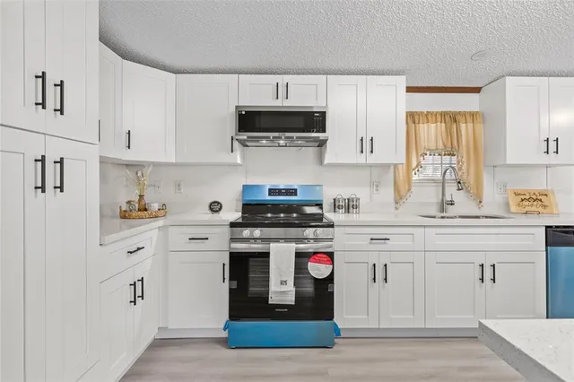 a kitchen with stainless steel appliances granite countertop a sink stove and refrigerator