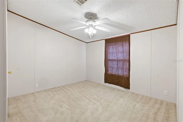 an empty room with a chandelier fan and closet