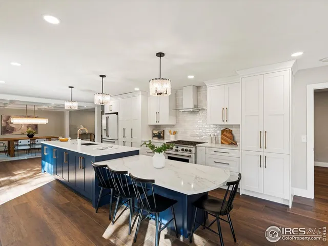 a view of a dining room and livingroom with furniture wooden floor a rug a painting and a chandelier