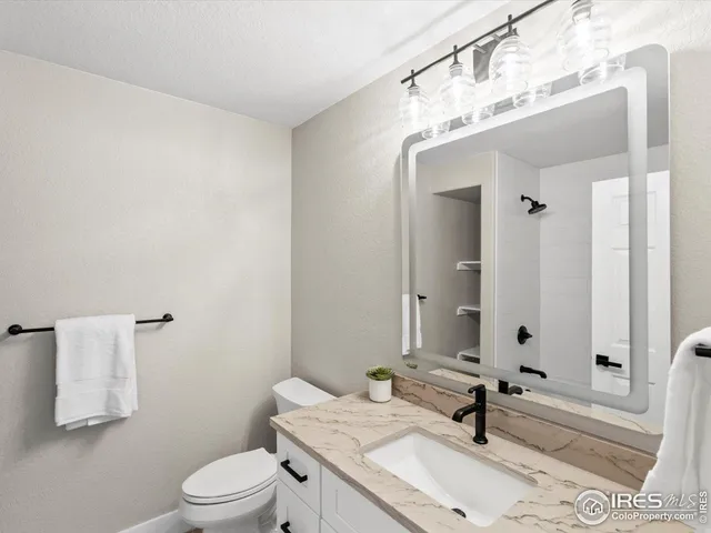 a bathroom with a granite countertop sink a toilet and mirror