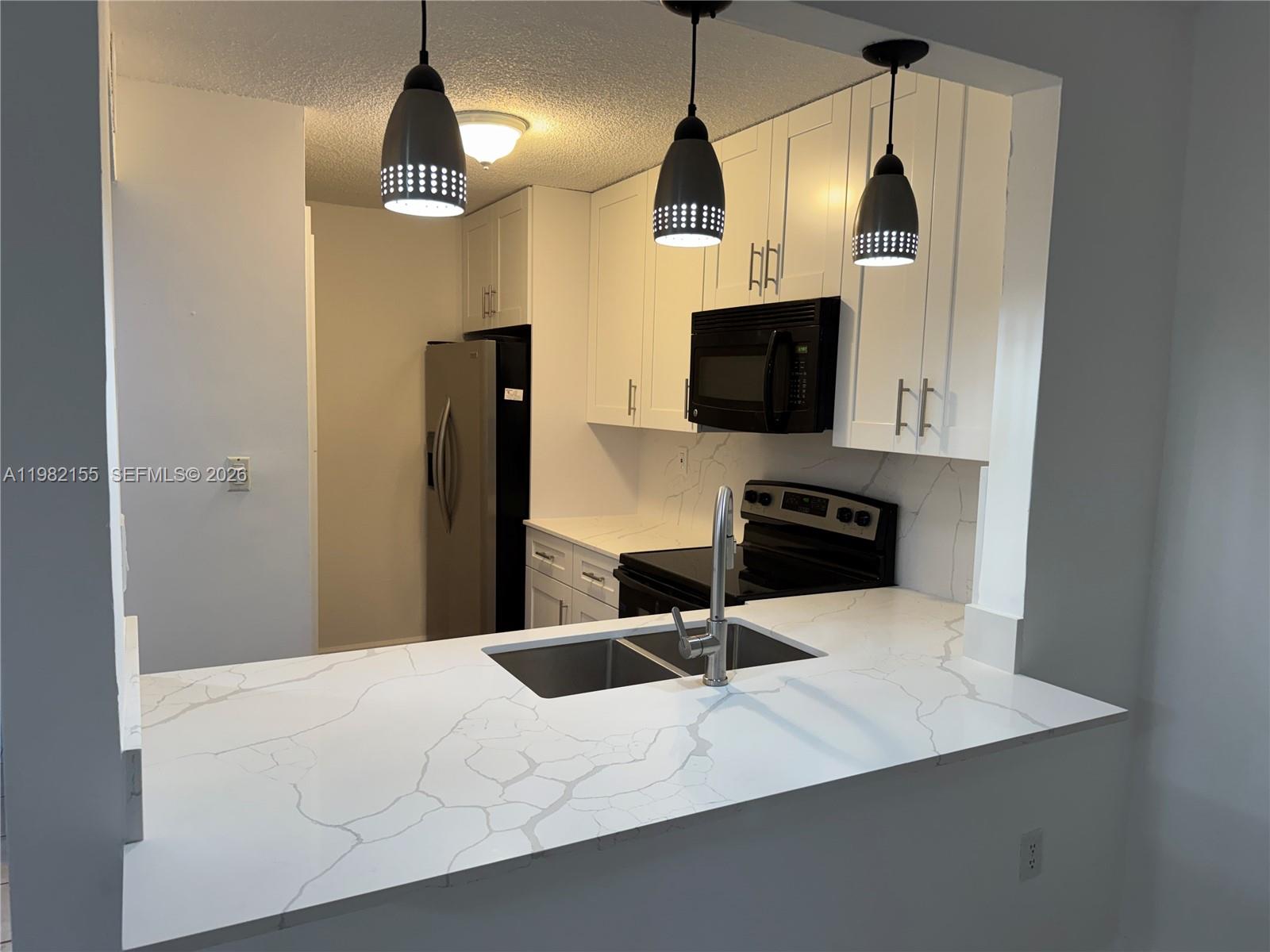 15610 Southwest 80th Street, Unit J105 Miami, FL 33193 - Photo 2 of 38 a kitchen with stainless steel appliances kitchen island granite countertop a refrigerator a sink a stove and microwave