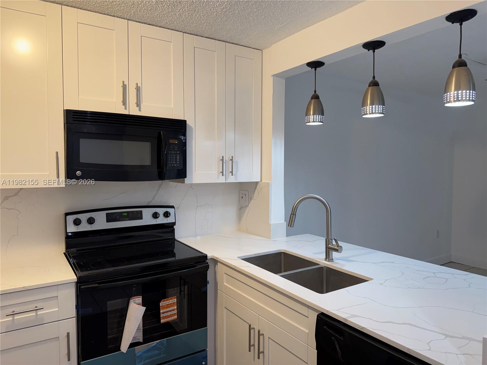 15610 Southwest 80th Street, Unit J105 Miami, FL 33193 - Photo 3 of 38 a kitchen with stainless steel appliances granite countertop a sink stove and microwave