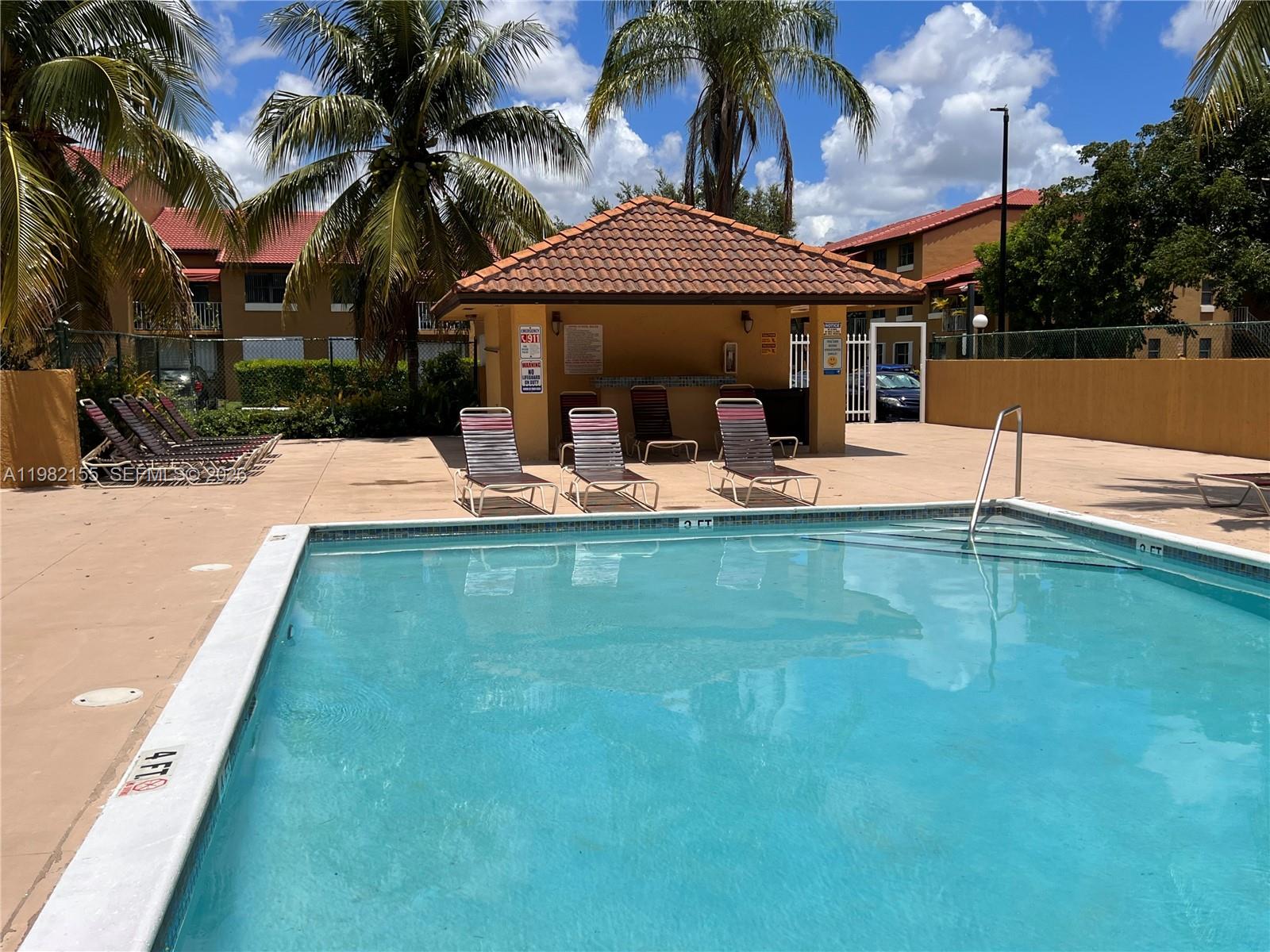 15610 Southwest 80th Street, Unit J105 Miami, FL 33193 - Photo 31 of 38 a view of a house with pool and chairs