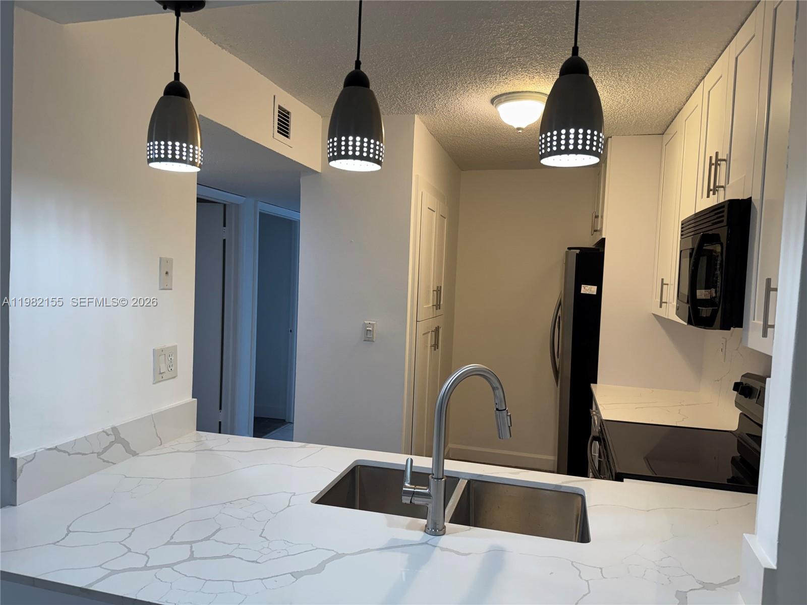 15610 Southwest 80th Street, Unit J105 Miami, FL 33193 - Photo 35 of 38 a kitchen with stainless steel appliances kitchen island a refrigerator a sink a stove and cabinets