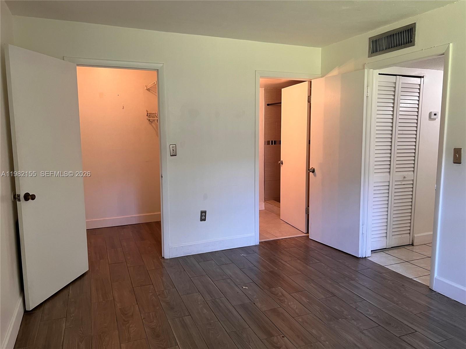 15610 Southwest 80th Street, Unit J105 Miami, FL 33193 - Photo 7 of 38 an empty room with wooden floor and closet