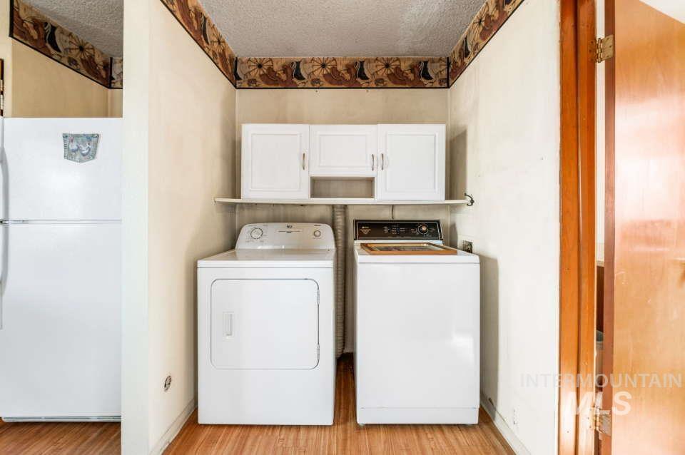 2026 Silcott Hills Road Clarkston, WA 99403 - Photo 15 of 29 Washroom featuring independent washer and dryer, cabinet space, light wood-type flooring, and a textured ceiling