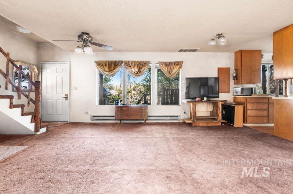 2026 Silcott Hills Road Clarkston, WA 99403 - Photo 8 of 29 Unfurnished living room with stairs, carpet flooring, and a ceiling fan