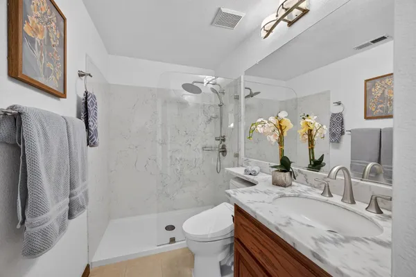 a spacious bathroom with a granite countertop sink a mirror and a bathtub