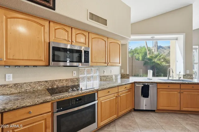 a kitchen with stainless steel appliances granite countertop wooden cabinets and a stove top oven