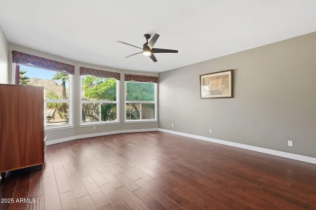 a view of empty room with wooden floor and fan