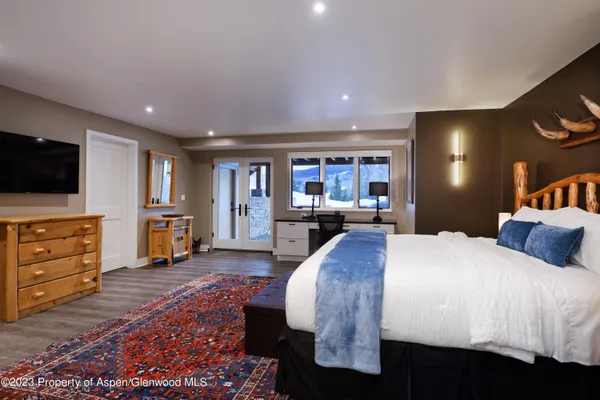a spacious bedroom with a bed and a flat screen television