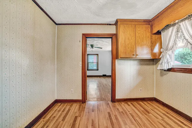 a view of empty room with wooden floor and fan