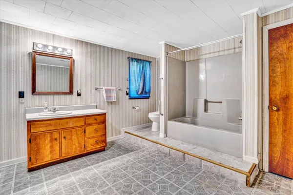 a spacious bathroom with a tub sink and mirror