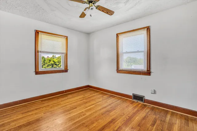 a view of an empty room with a window and wooden floor