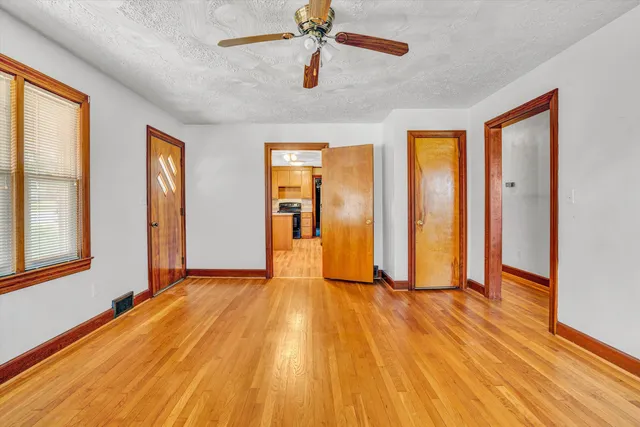 a view of an empty room with wooden floor and a window