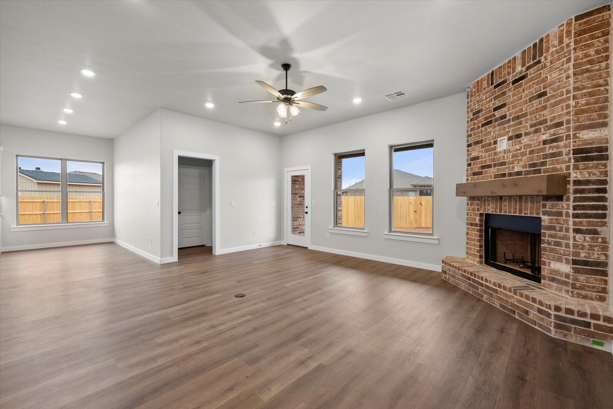 7436 30th Street Lubbock, TX 79407 - Photo 12 of 25 an empty room with windows fireplace and a kitchen view