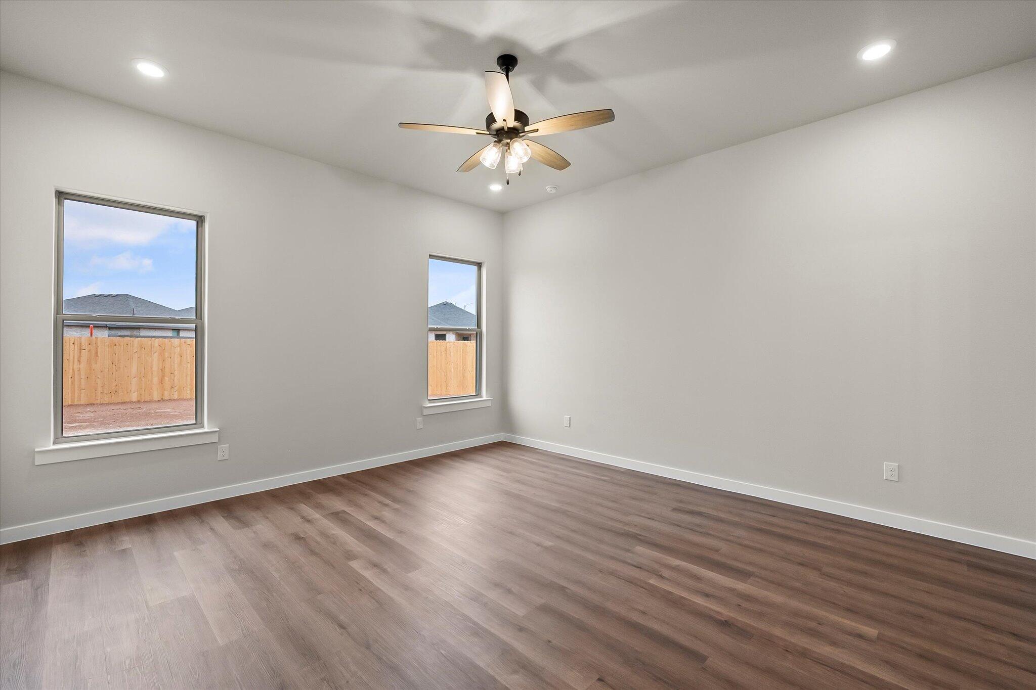 7436 30th Street Lubbock, TX 79407 - Photo 13 of 25 an empty room with wooden floor chandelier fan and windows