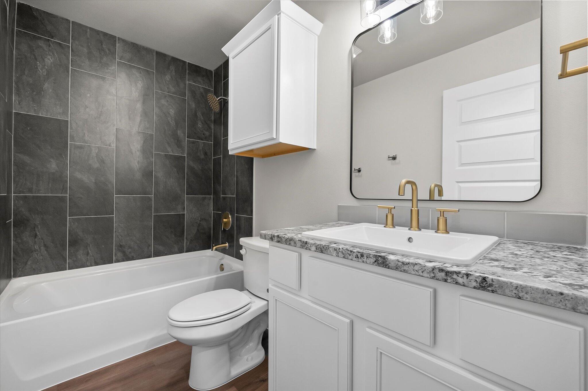 7436 30th Street Lubbock, TX 79407 - Photo 21 of 25 a bathroom with a granite countertop sink a toilet and bathtub