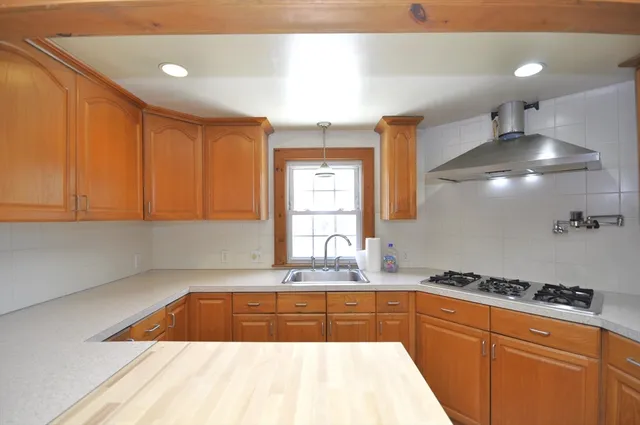 a kitchen with granite countertop a sink a stove and cabinets