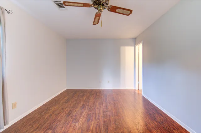 a view of empty room with wooden floor and ceiling fan