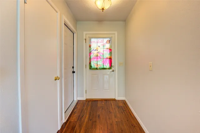 a view of a hallway with wooden floor and a bathroom