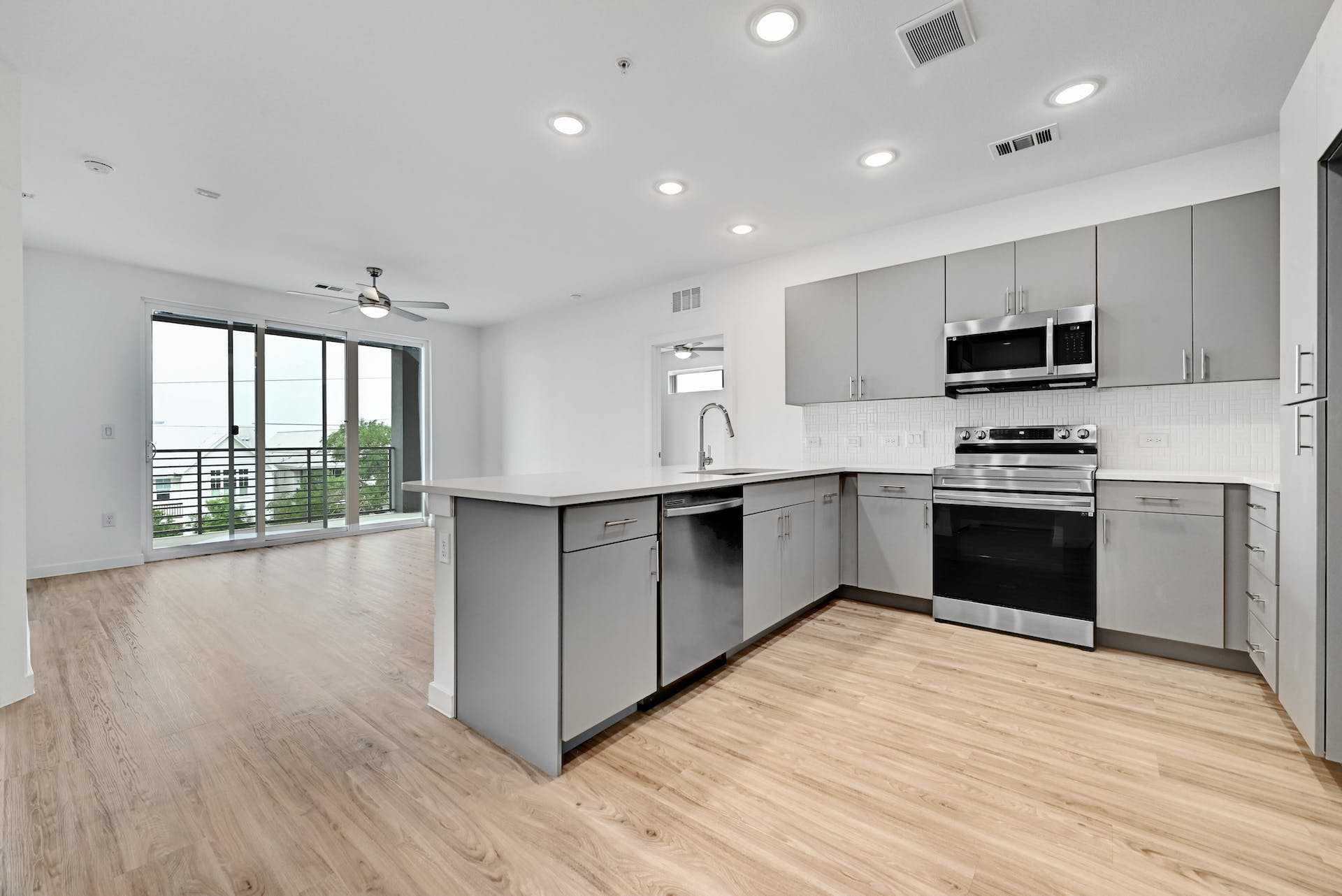 4801 Springdale Road, Unit 1301 Austin, TX 78723 - Photo 2 of 39 A well-appointed kitchen island flows into a living space with abundant natural light and balcony access.