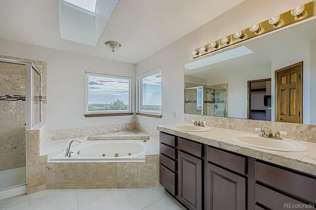 a bathroom with a granite countertop tub sink and mirror