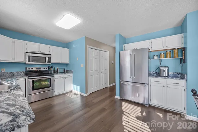 a kitchen with granite countertop white cabinets and white appliances
