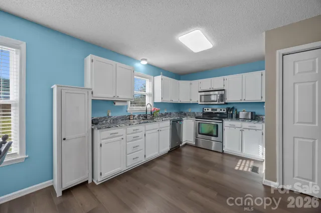 a kitchen with granite countertop cabinets stainless steel appliances a sink and a window