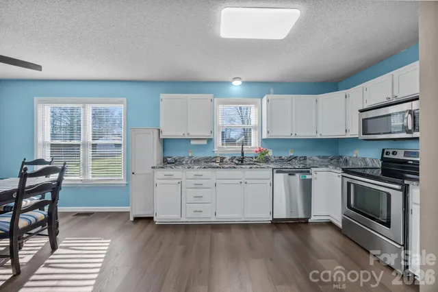 a kitchen with stainless steel appliances granite countertop a sink stove microwave and refrigerator